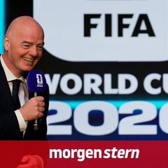 Gianni Infantino steht vor dem Logo der Fußball-WM 2026 in den USA, Kanada und Mexiko