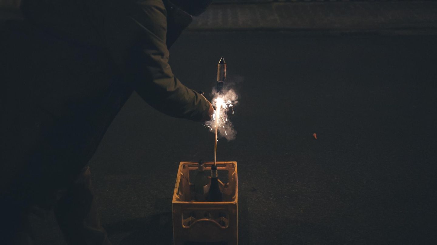 Person zündet eine Feuerwerksrakete an