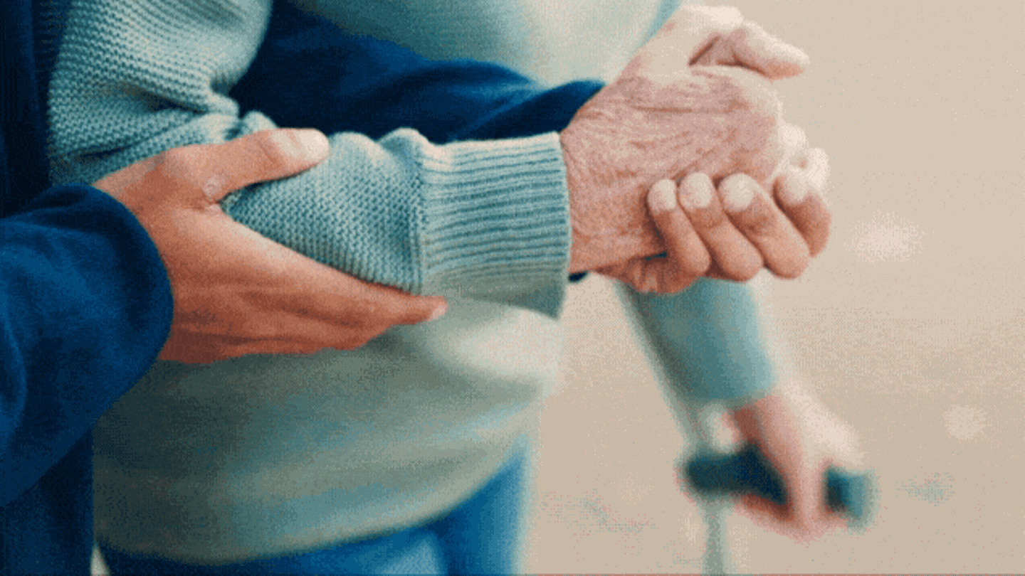 Pflegeversicherung: Stützende Hände helfen einer alten Person