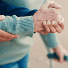 Pflegeversicherung: Stützende Hände helfen einer alten Person