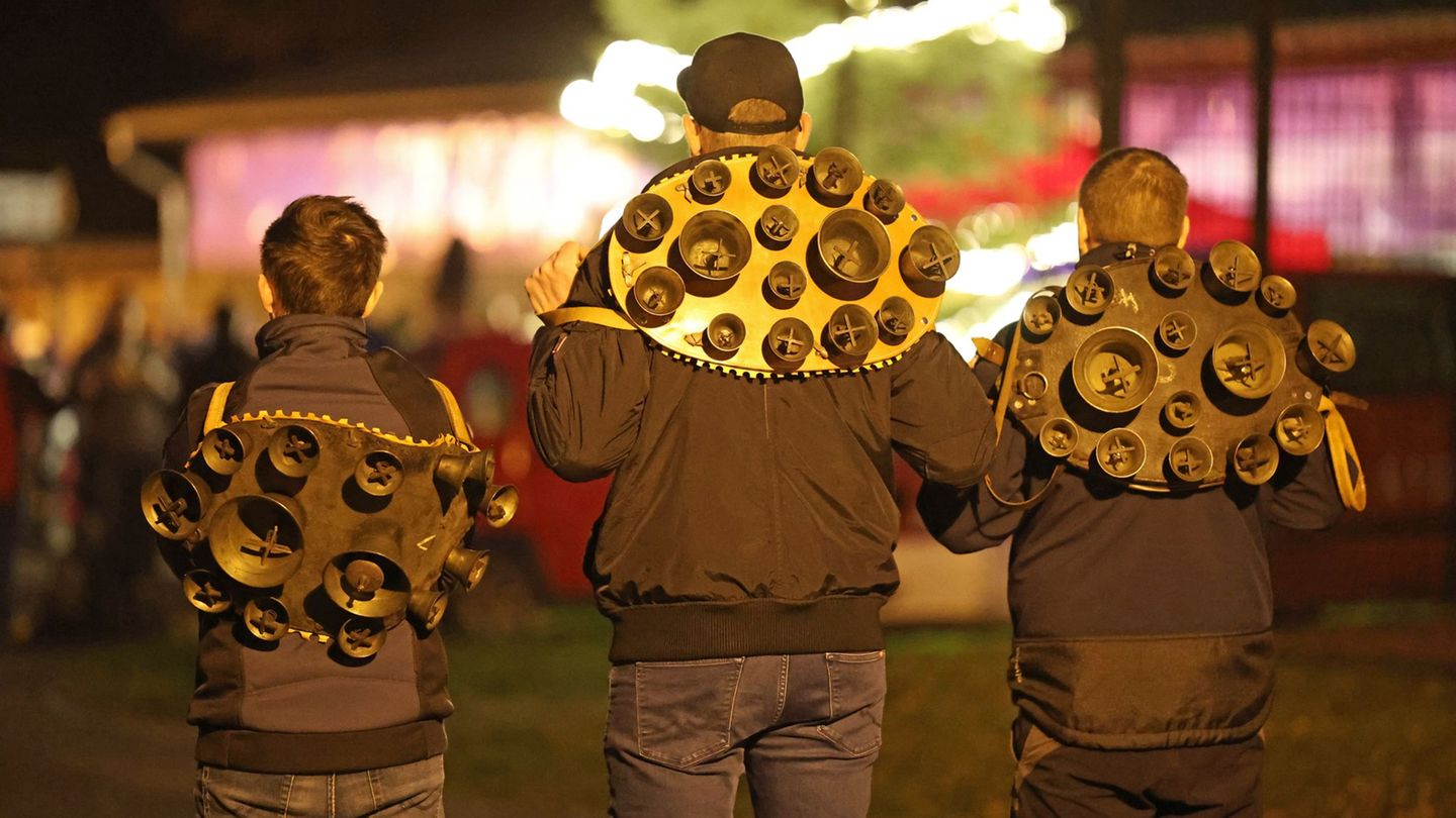 Drei Mitglieder der Brauchtumsgruppe Weihnachtsmänner e.V. stehen mit Schellengeläut auf dem Weihnachtsmarkt in Altenbrak. Am er
