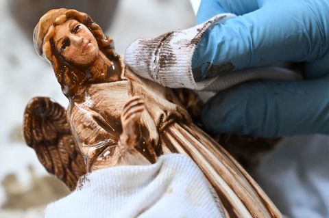 Einer Figur aus Papiermaché wird in der Marolin Manufaktur Steinach von Hand die Patina mit weichen Lappen von der Oberfläche ge