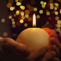 Hand hält Kerze  in weihnachtlicher Umgebung