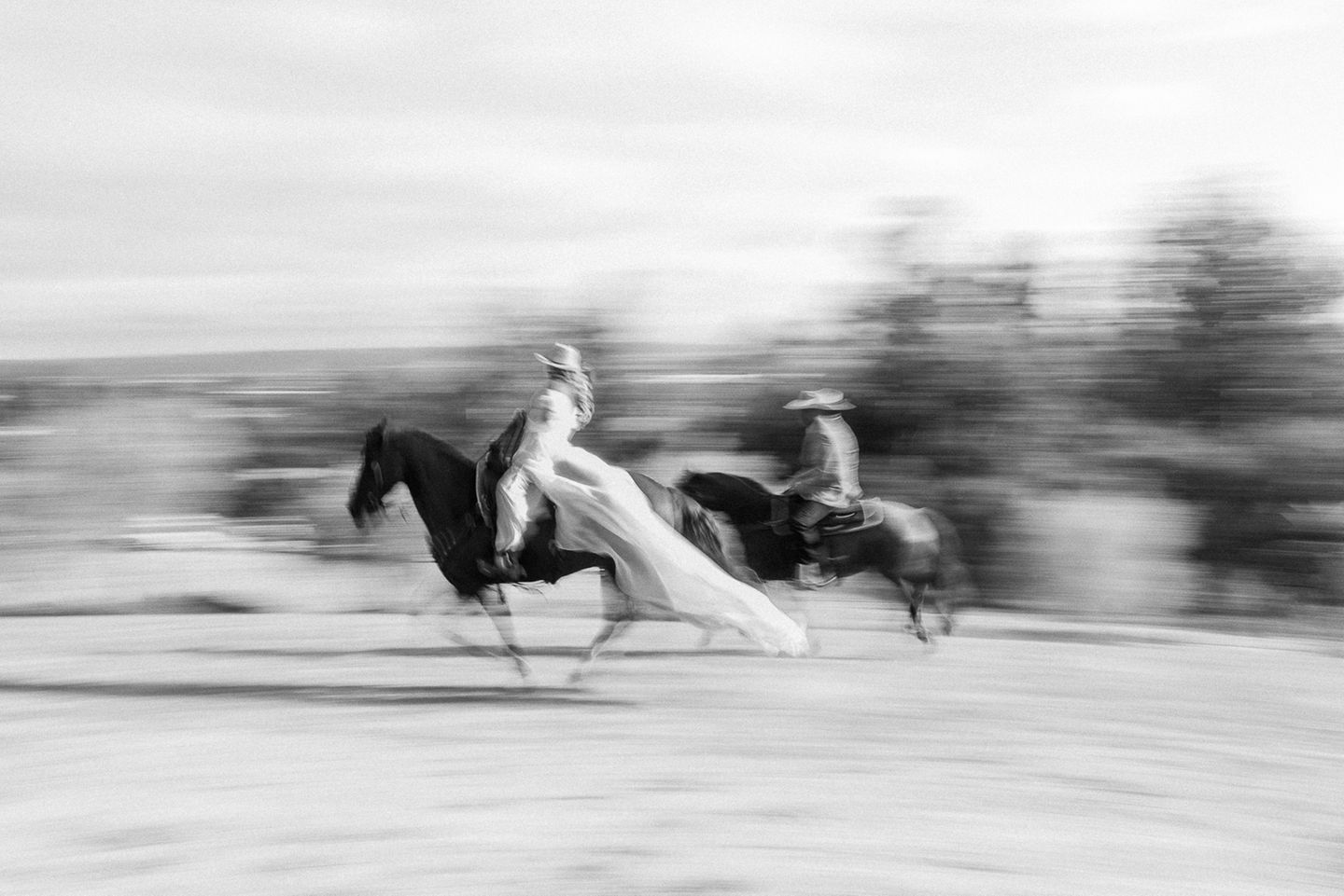 Zwei Personen reiten in Hochzeitskleidung auf Pferden