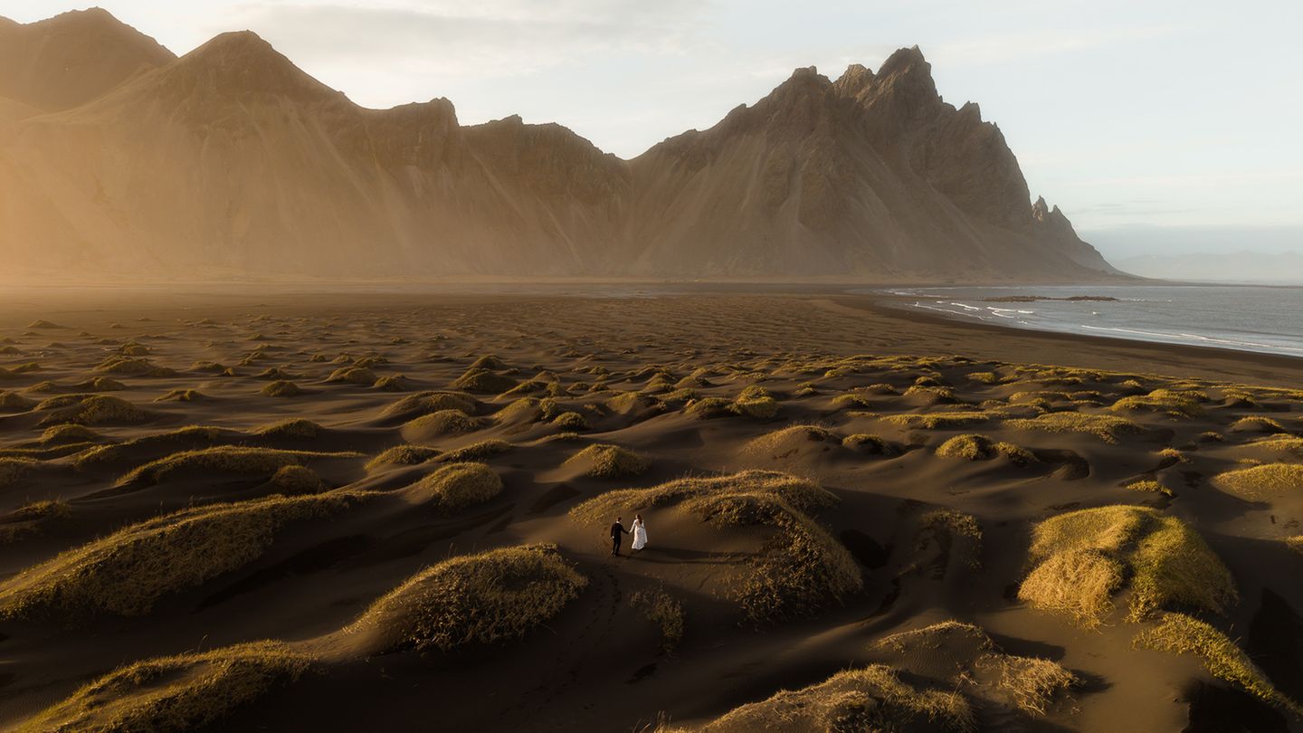 Ein hügeliger Küstenabschnitt, durch den zwei Menschen laufen
