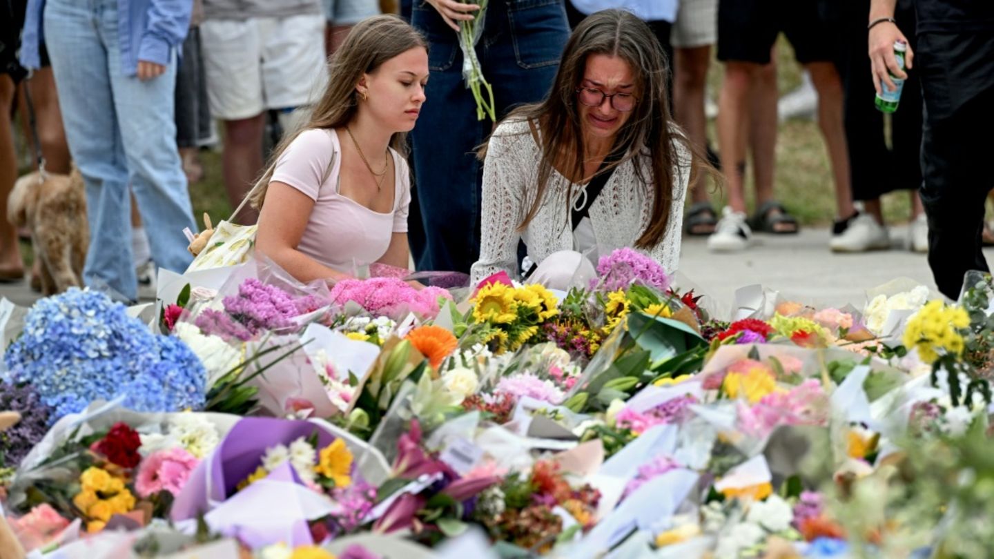 Menschen legen am Anschlagsort Blumen nieder