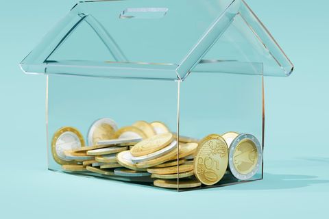 Illustration zum Hauskauf: Ein Sparschwein in Form eines Hauses mit Geld