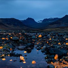 Sodalithsteine leuchten in einer Landschaft im Süden Grönlands in der Dämmerung