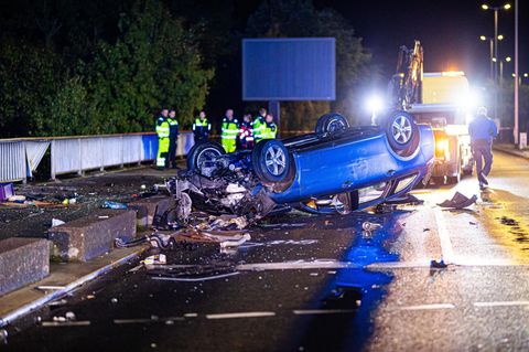 Ein Auto liegt nach einem Unfall auf einer Autobahn verkehrt herum auf dem Fahrstreifen