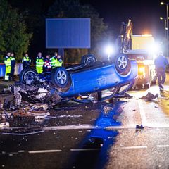 Ein Auto liegt nach einem Unfall auf einer Autobahn verkehrt herum auf dem Fahrstreifen