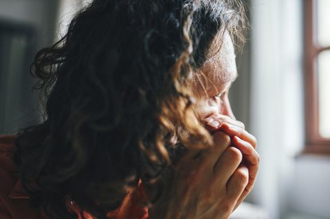 Eine Frau schaut nachdenklich aus dem Fenster. Ist sie auf Kreuzfahrt?