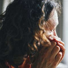 Eine Frau schaut nachdenklich aus dem Fenster. Ist sie auf Kreuzfahrt?