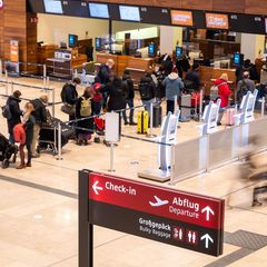 Menschen stehen am Check-In Schalter am Flughafen Berlin Brandenburg (Symbolbild)