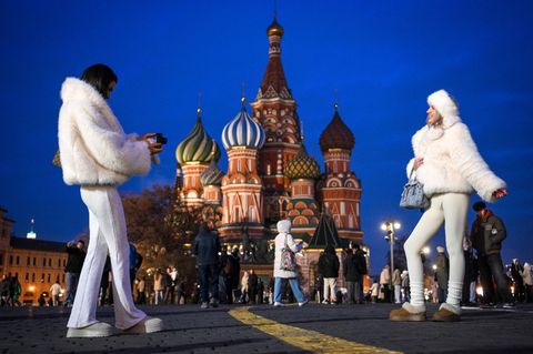 zwei junge Frauen stehen vor der Kathedrale in Moskau und fotografieren sich