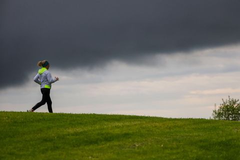 Eine Joggerin läuft an einer Wiese vorbei