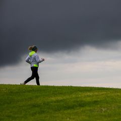 Eine Joggerin läuft an einer Wiese vorbei