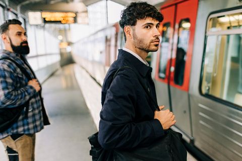 Handwerker und Büroangestellter stehen am Bahnsteig, wo gerade die U-Bahn eingefahren ist – wer hat mehr Gehalt?