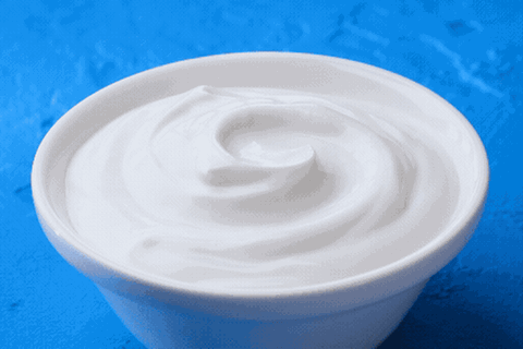 Ein Becher Joghurt, in den ein Löffel eintaucht (Animation)