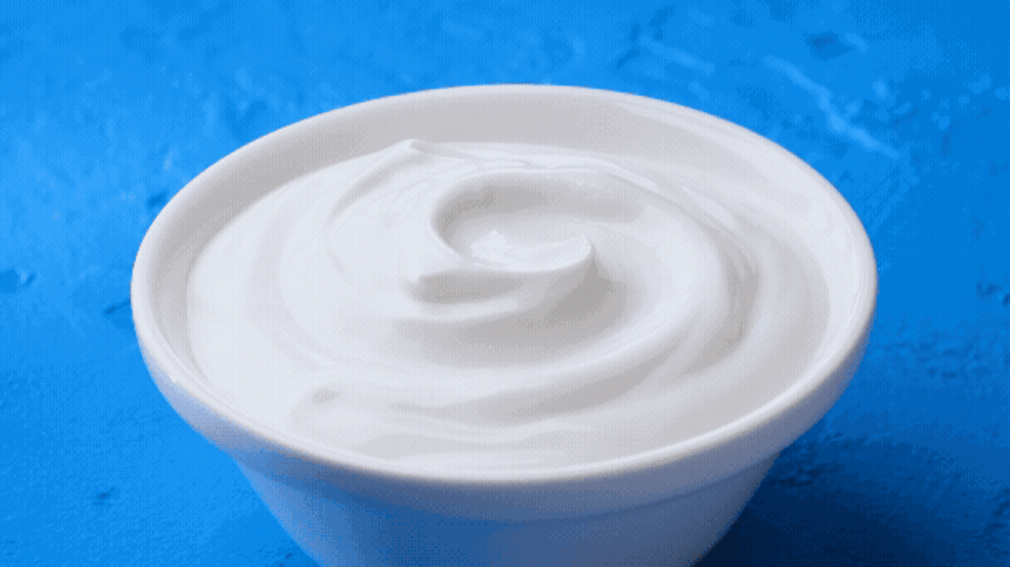 Ein Becher Joghurt, in den ein Löffel eintaucht (Animation)