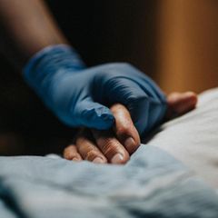 Palliativmedizin bei Patrice Aminati: eine Pflegerin umfasst die Hand einer Patientin (Symbolbild)