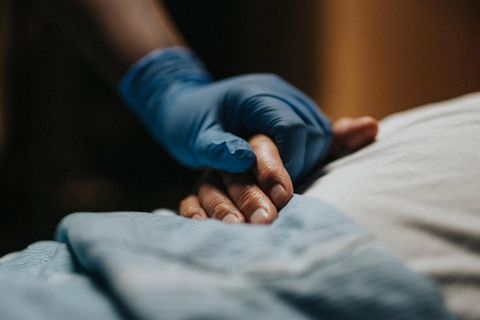 Palliativmedizin bei Patrice Aminati: eine Pflegerin umfasst die Hand einer Patientin (Symbolbild)