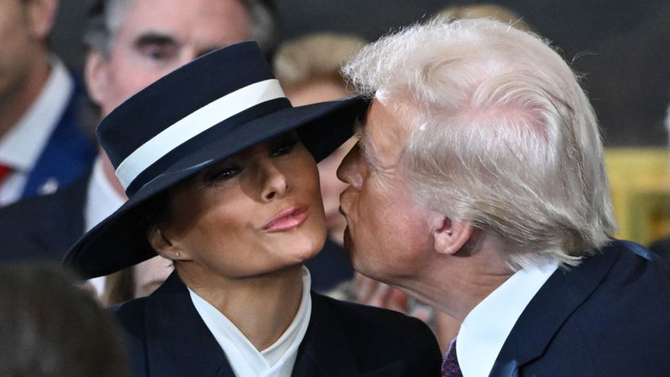 Donald Trump und Melania Trump versuchen sich zu küssen, kommen aber wegen des Hutes nicht heran