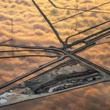 Vor Jahrhunderten gewannen die Mitglieder des Stammes der Ohlone Salz aus den natürlichen Gezeitentümpeln der San Francisco Bay. Im 19. Jahrhundert veränderten europäische Siedler die Region, indem sie weite Teile des Feuchtgebiets mit Deichen abriegelten und es zu einem der größten Salzproduktionsstandorte der Welt machten. In ihrer Blütezeit beanspruchte diese Industrie über 14.000 Hektar – was den Verlust von fast 85 Prozent der ursprünglichen, artenreichen Gezeitensümpfen der Bucht zur Folge hatte. Im Jahr 2003 markierte das South Bay Salt Pond Restoration Project einen Wendepunkt: Mit dem Erwerb von fast 6000 Hektar Salzbecken von Cargill, einem multinationalen Lebensmittelkonzern, der immer noch etwa eine halbe Million Tonnen Salz pro Jahr gewinnt, begannen die Bemühungen, den Einfluss der Gezeiten langsam wiederherzustellen. Durch die Öffnung von Deichen kehren die ursprünglichen Ökosysteme allmählich zurück