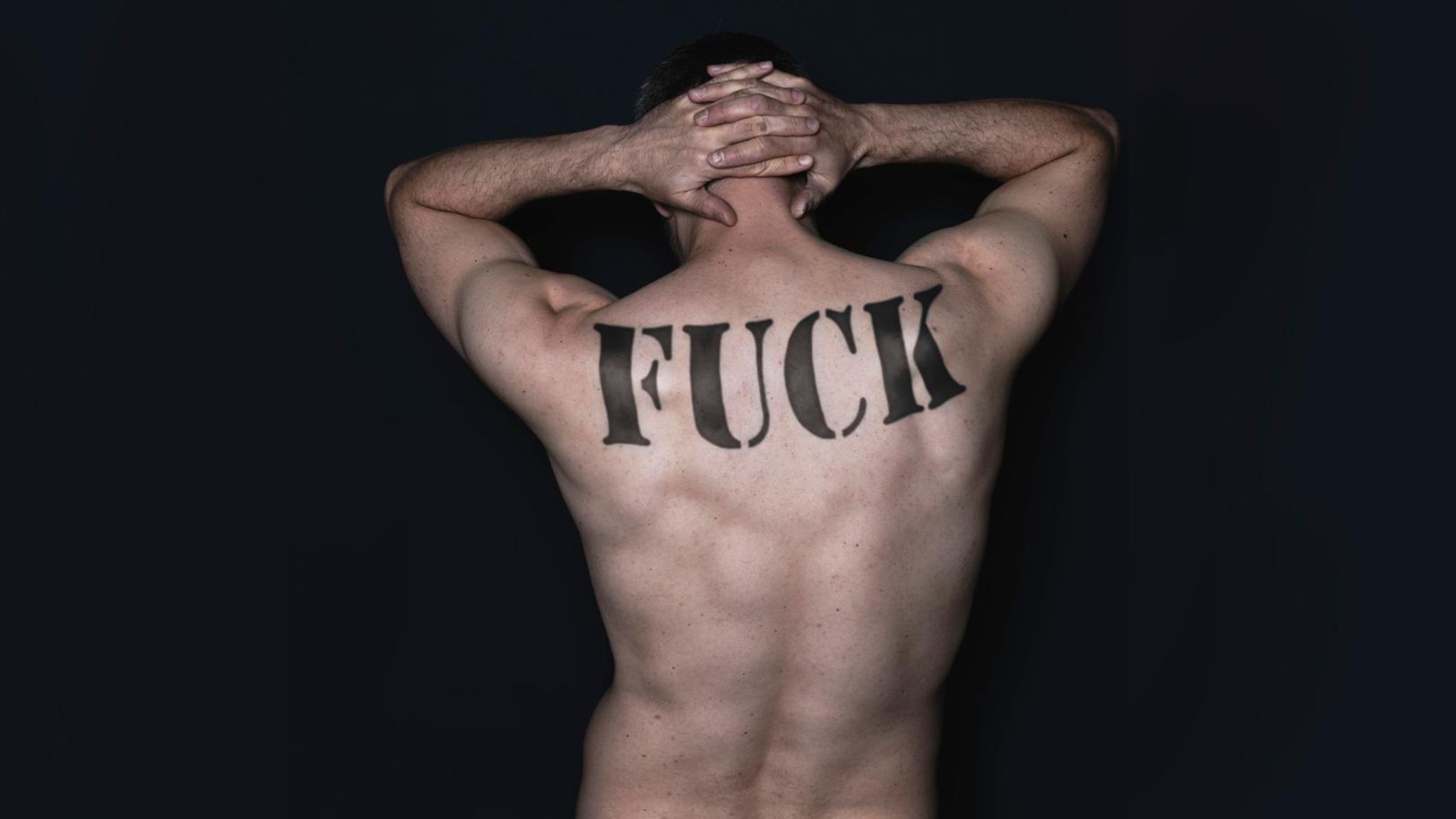 Ein männlicher Rücken mit einem "Fuck"-Tattoo