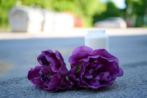 Blumen und eine Kerze liegen nach der Tat vor dem Spielplatz in Menden