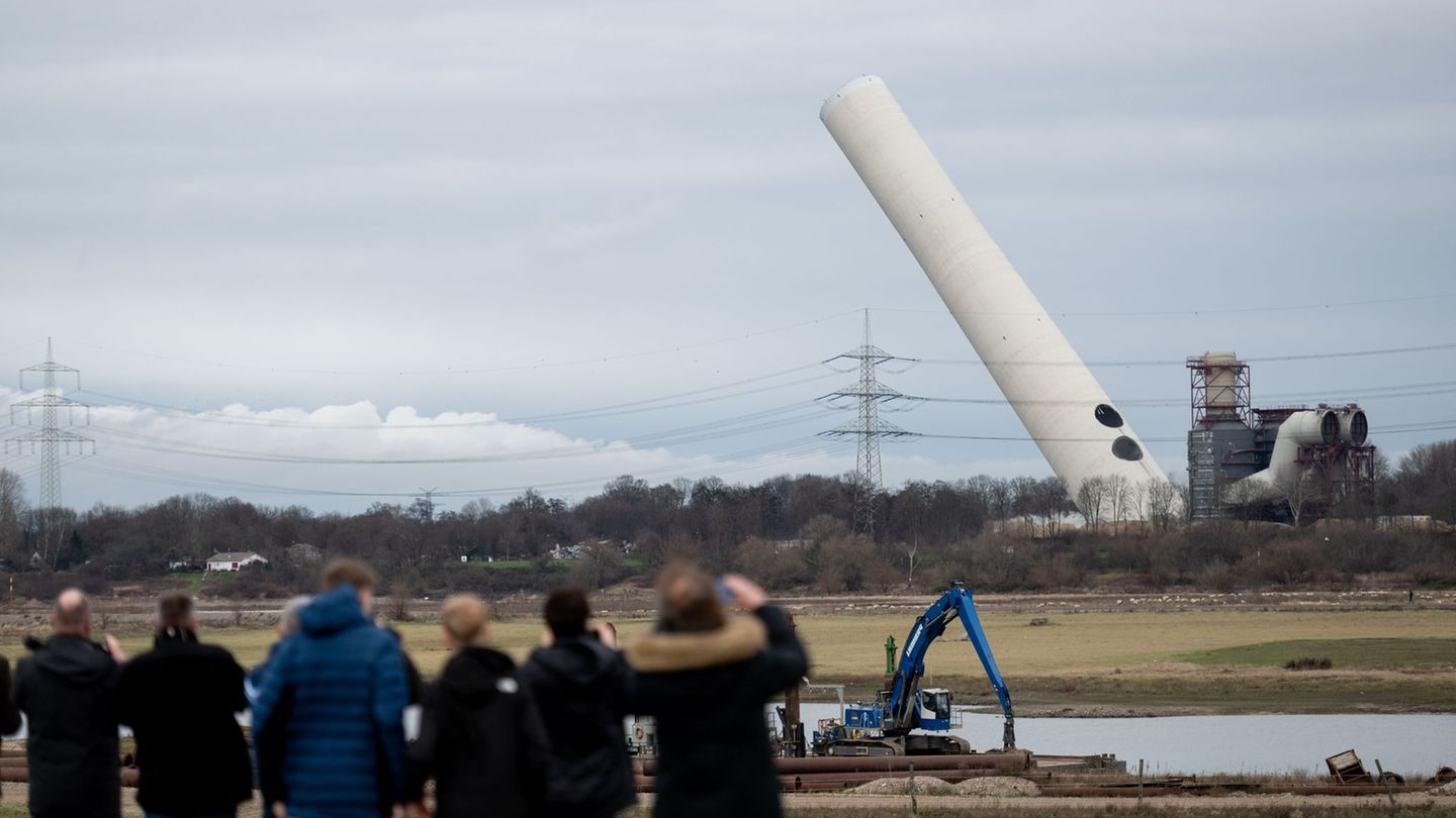 Der 180-Meter-Kamin kippt nach der Sprengung langsam um. Foto: Fabian Strauch/dpa