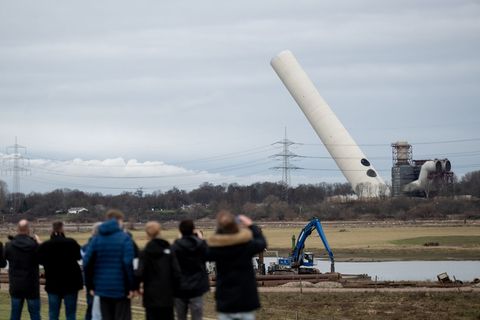 Der 180-Meter-Kamin kippt nach der Sprengung langsam um. Foto: Fabian Strauch/dpa