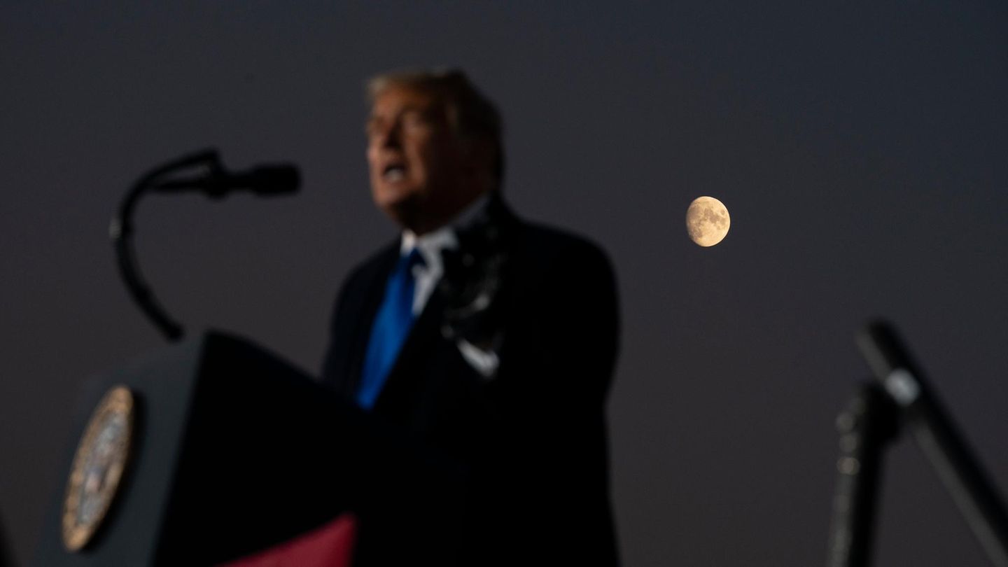 Donald Trump spricht vor dunkler Kulisse, hinter ihm ist der Mond zu sehen