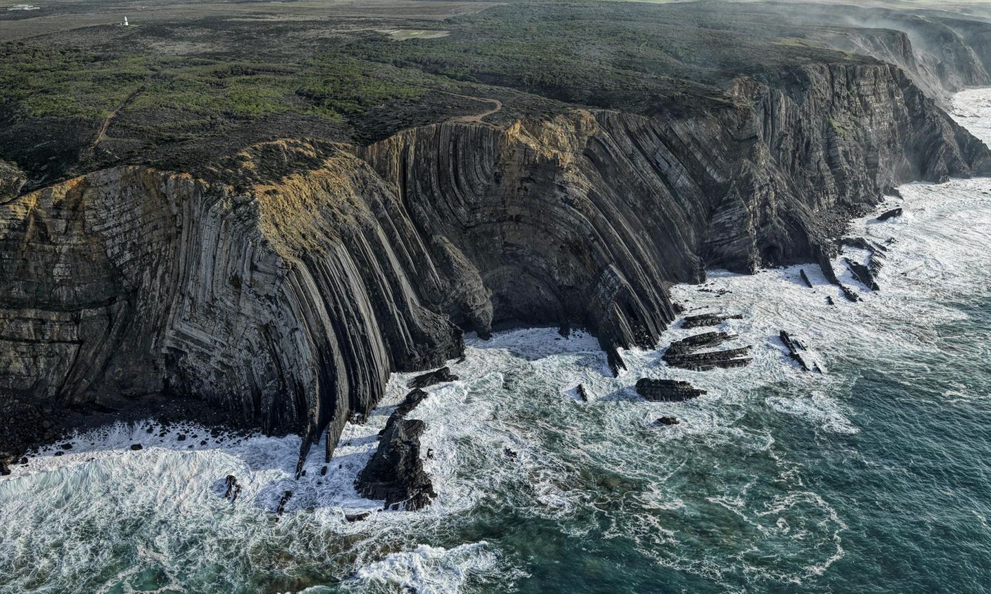 Im Winter fegen kräftige Stürme über die portugiesische Costa Vicentina und sorgen dafür, dass sich weit draußen im Atlantik meterhohe Wellen auftürmen. Wenn diese an die bis zu 30 Meter hohe Steilküste im wilden Westen der Algarve gepeitscht werden und dort mit großer Wucht an den Felsen zerschellen, dringt das Meerwasser in jede noch so kleine Ritze der Felswände ein. Das salzige Wasser spült die Fugen aus und zermürbt mit der Zeit selbst das härteste Gestein. Dennoch gilt die Costa Vicentina als der am besten erhaltene Küstenstreifen Europas, der über 200 Vogelarten ein Zuhause bietet