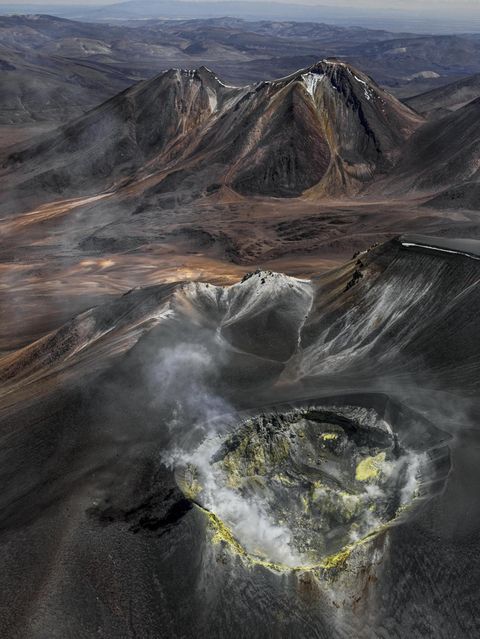 Wie eine eiternde Wunde klafft der Vulkankrater auf dem Gipfel des Isluga, der sich über der kahlen Landschaft des Altiplano an der Grenze zwischen Chile und Bolivien erhebt. Gasschwaden treten aus seinem Inneren; gelb gefärbtes Gestein an den Kraterwänden bezeugt die Schwefelvorkommen, die hier vor einigen Jahrzehnten noch abgebaut wurde. Bernhard Edmaier fotografierte den gewaltigen Krater mit einem Durchmesser von 400 Metern aus der Vogelperspektive und dabei Wissenschaft und Kunst vereint. Der Fotograf und Geologe zeigt mit seinen spektakulären Luftaufnahmen im Bildband "Elements", mit welcher Macht die Natur Landschaften formt – nicht nur hier, in der Hochebene der Anden, sondern auf allen Kontinenten 