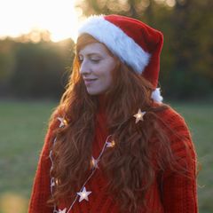 Eine junge mit einer Nikolaus-Mütze Frau blickt traurig