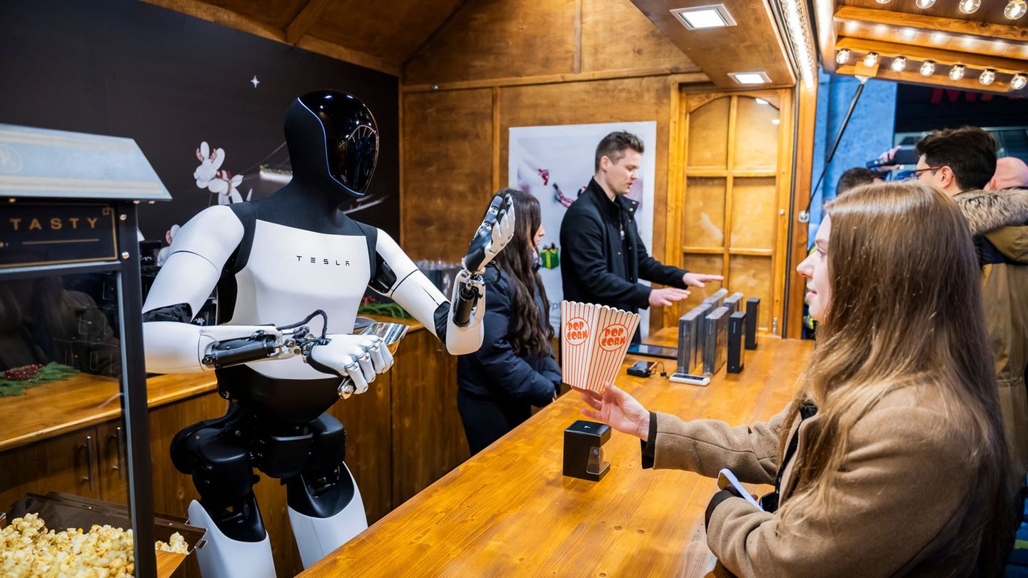 Der humanoide Roboter "Optimus" von Tesla verteilt bei seiner Vorstellung in der Mall of Berlin Popcorn an eine Besucherin. Foto