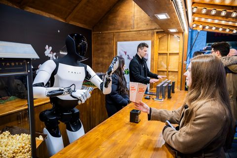 Der humanoide Roboter "Optimus" von Tesla verteilt bei seiner Vorstellung in der Mall of Berlin Popcorn an eine Besucherin. Foto