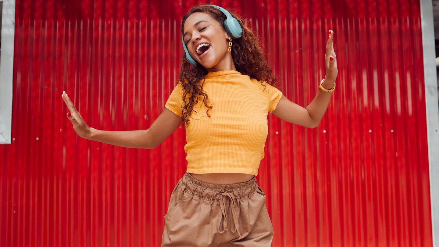 Musik hören: eine junge Frau mit Kopfhörern tanzt