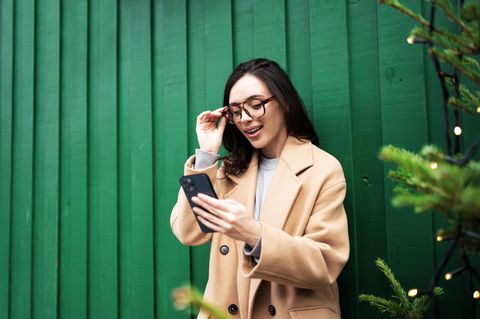 Eine Frau nutzt Whatsapp vor weihnachtlicher Kulisse