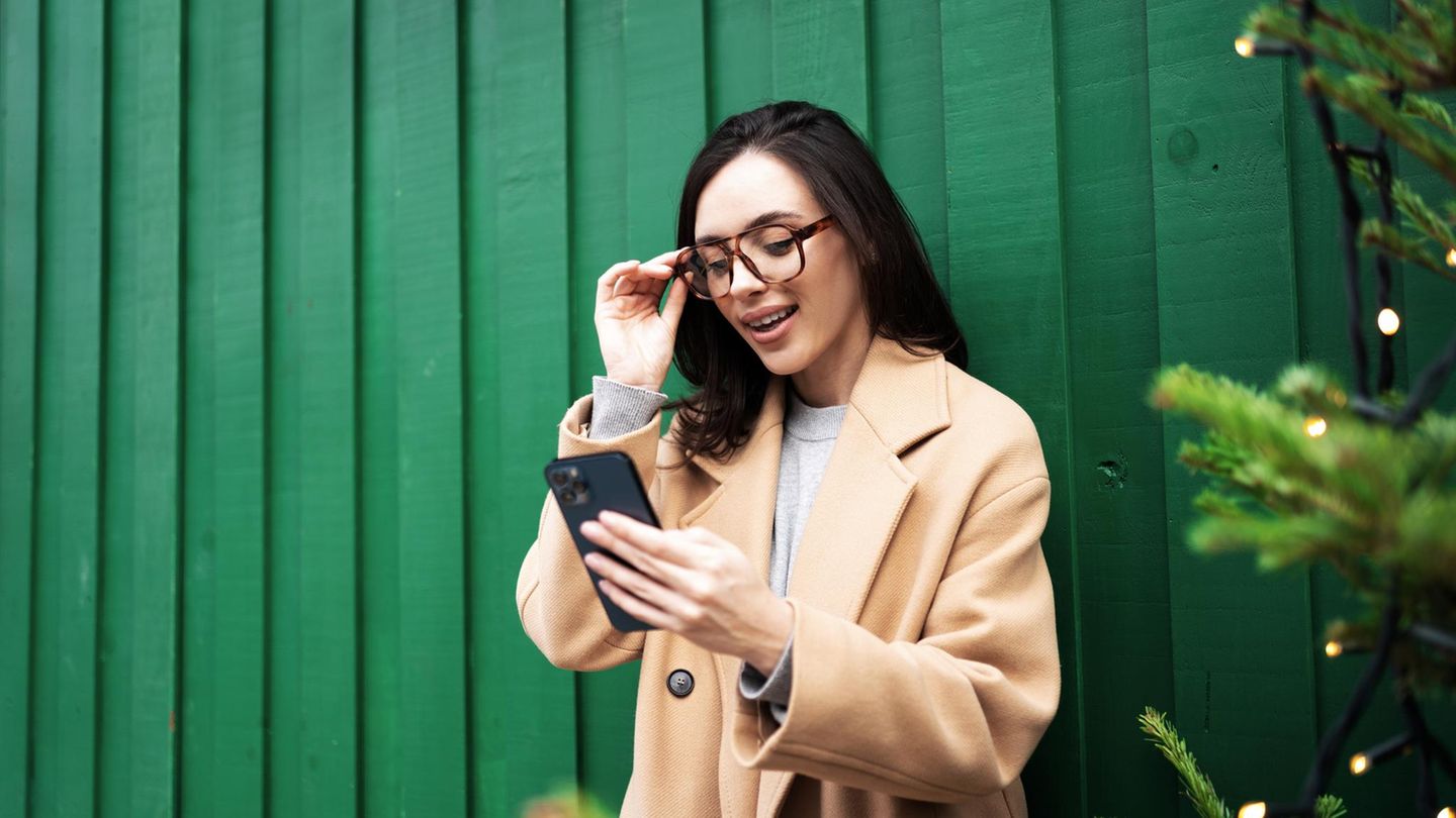 Eine Frau nutzt Whatsapp vor weihnachtlicher Kulisse