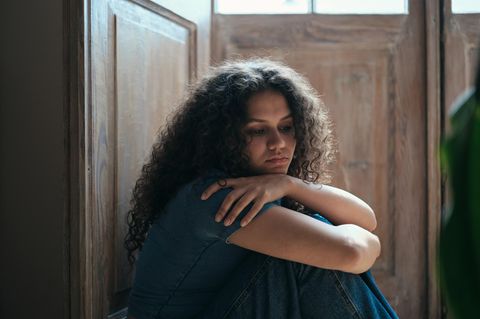 Mutter: Junge Frau an Türrahmen gelehnt mit verschränkten Armen