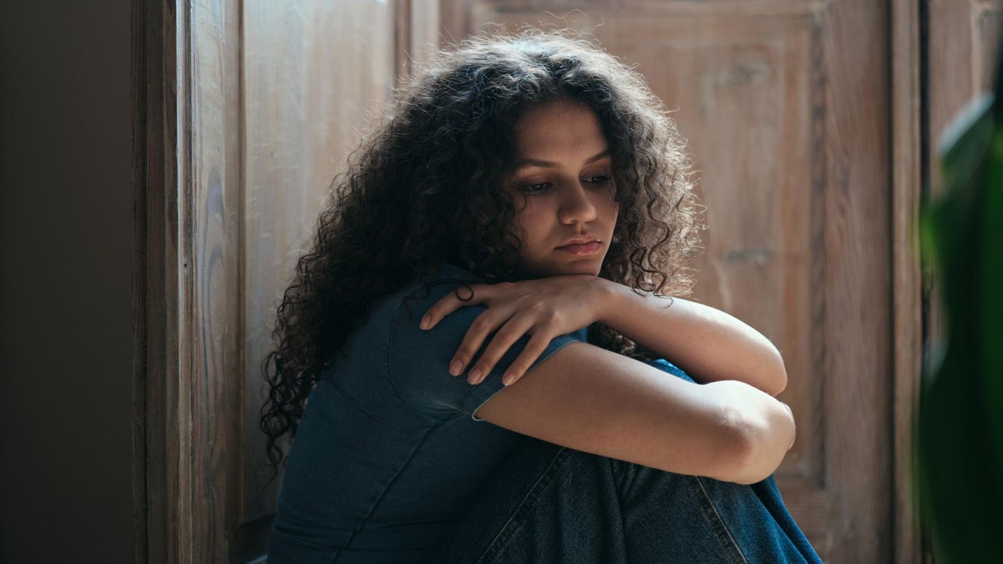 Mutter: Junge Frau an Türrahmen gelehnt mit verschränkten Armen