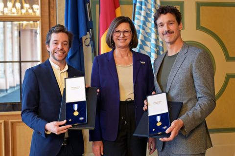 Landtagspräsidentin Ilse Aigner (CSU) zeichnet Tobias Krell und Florian David Fitz bei einem Nachholtermin mit dem Bayerischen V