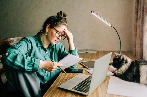 Bürokratie: Eine Frau blickt nachdenklich auf mehrere Dokumente vor sich