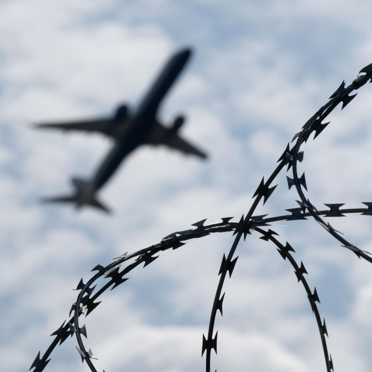 Ein Flugzeug startet hinter einem Zaun mit Natodraht – Symbolbild Abschiebung nach Syrien