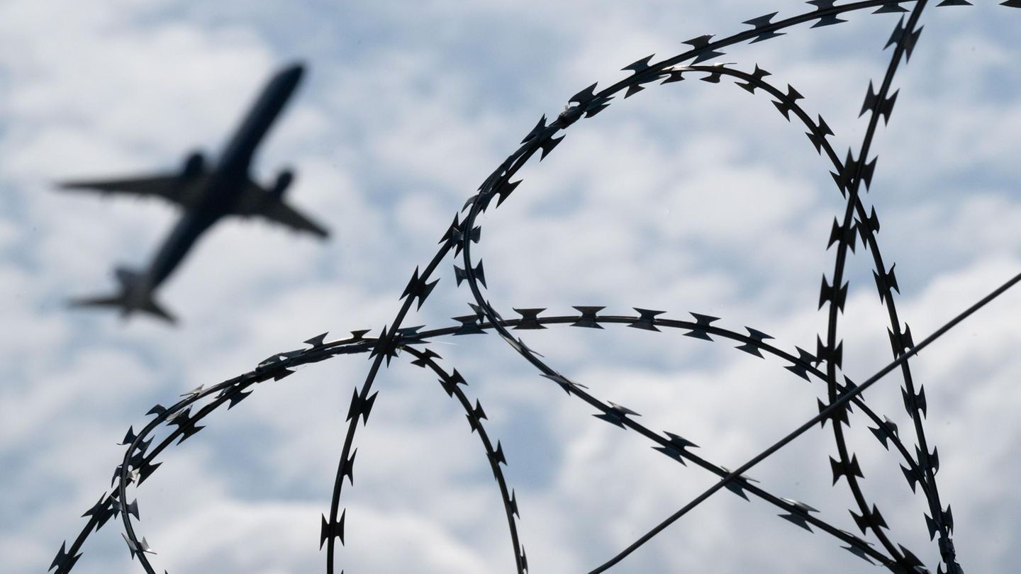 Ein Flugzeug startet hinter einem Zaun mit Natodraht – Symbolbild Abschiebung nach Syrien