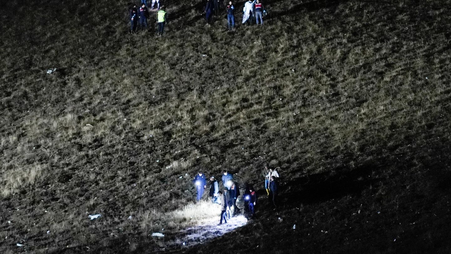 Eine dunkle Wiese wird von Menschen untersucht