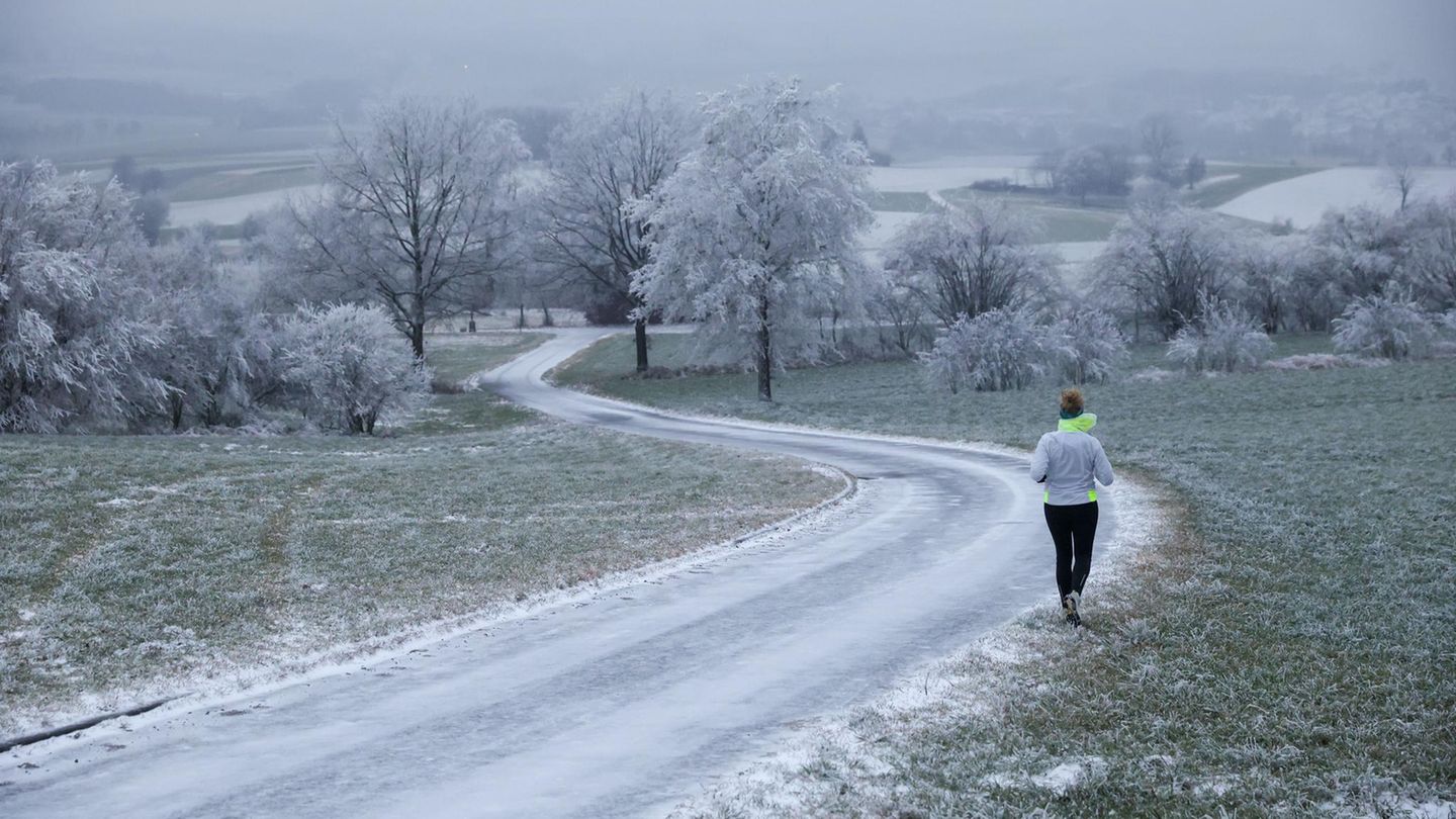 Uttenweiler, Deutschland. Eine Joggerin ist an Heiligabend in der mit Schnee und Raureif bedeckten Landschaft unterwegs. Es ist kalt wie lange nicht an diesem heiligen Tag, und frühmorgens wirkt die Natur fast weiß. Nur richtig viel Schnee fehlt, trotzdem sieht es ein bisschen wie weiße Weihnacht aus