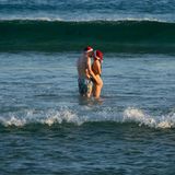 Sydney, Australien. Ein Liebespaar mit Weihnachtsmützen küsst sich in den Fluten am Bondi Beach. Im hochsommerlichen Australien ist es üblich, an Weihnachten und zwischen den Tagen an den Strand zu gehen. Diesmal fällt es allerdings schwerer. Noch immer herrscht Trauer um der Opfer des antisemitischen Terroranschlags, bei dem ein Vater und sein Sohn im Auftrag des IS 15 Juden während der Chanukka-Feier erschossen      