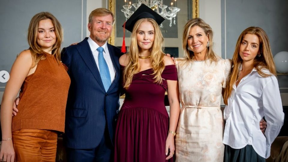 Amalia steht inmitten ihrer Familie und trägt einen Absolventenhut